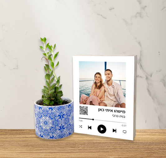 Framed photo of a couple on a boat with a plant in a blue pot on a wooden surface.