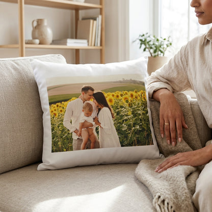 Person sitting on a couch with a pillow featuring a family in a sunflower field