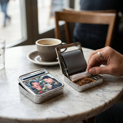 Person opening a small metal case on a marble table with a cup of coffee in the background.